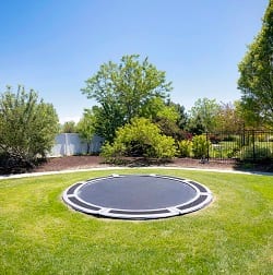 Penere hage med en nedgravd trampoline